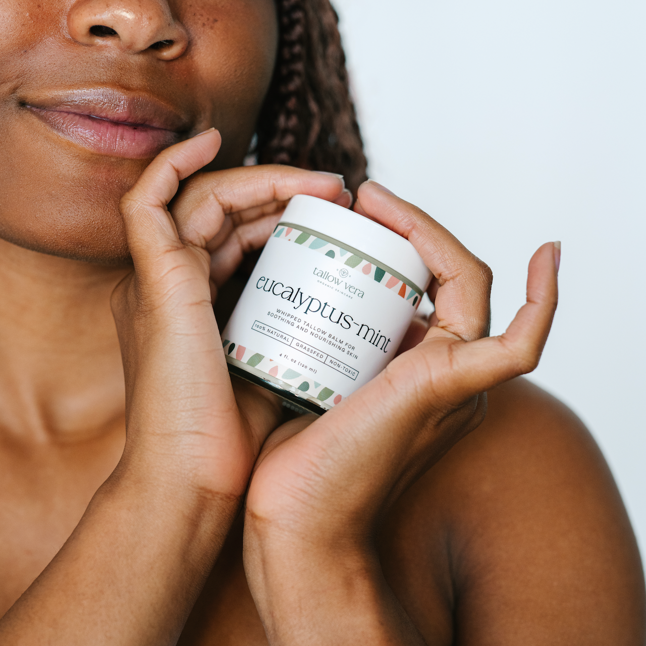 Girl holding a jar of Tallow Vera's eucalyptus mint tallow balm close to her face