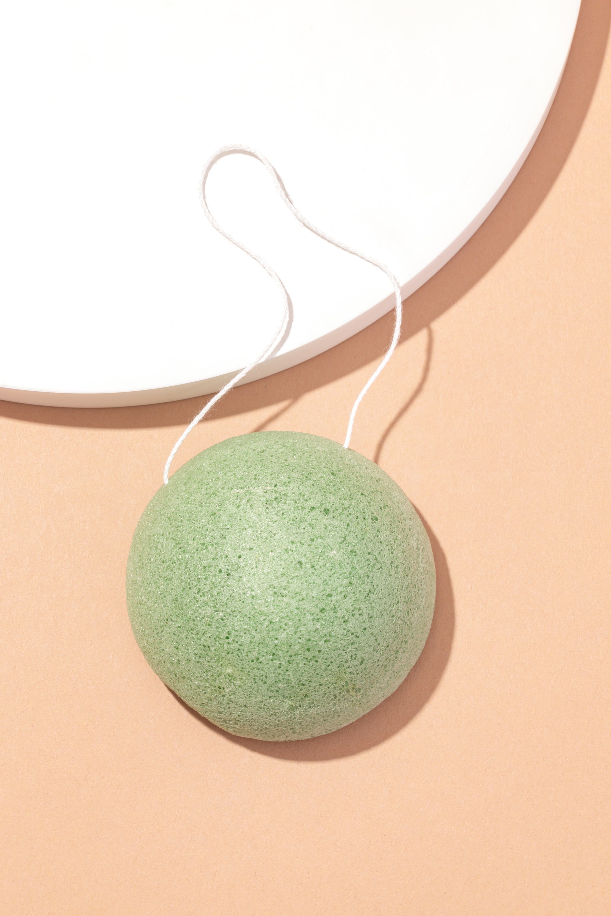 Green konjac sponge on a beige background