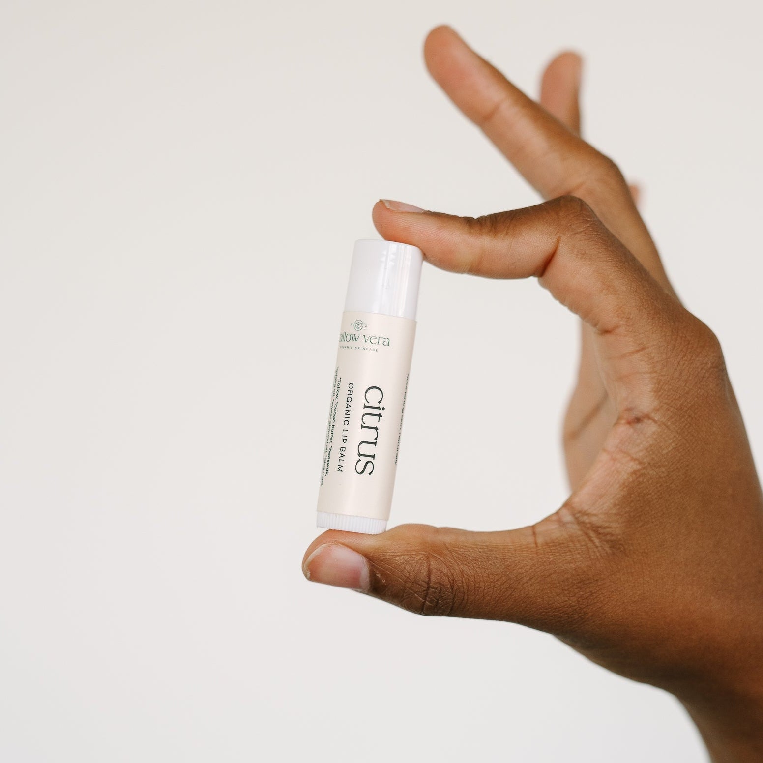Hand holding a Tallow Vera citrus tallow lip balm tube