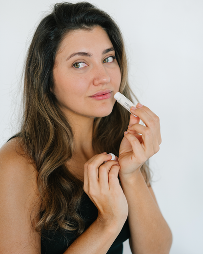 Woman applying tallow lip balm with a white background