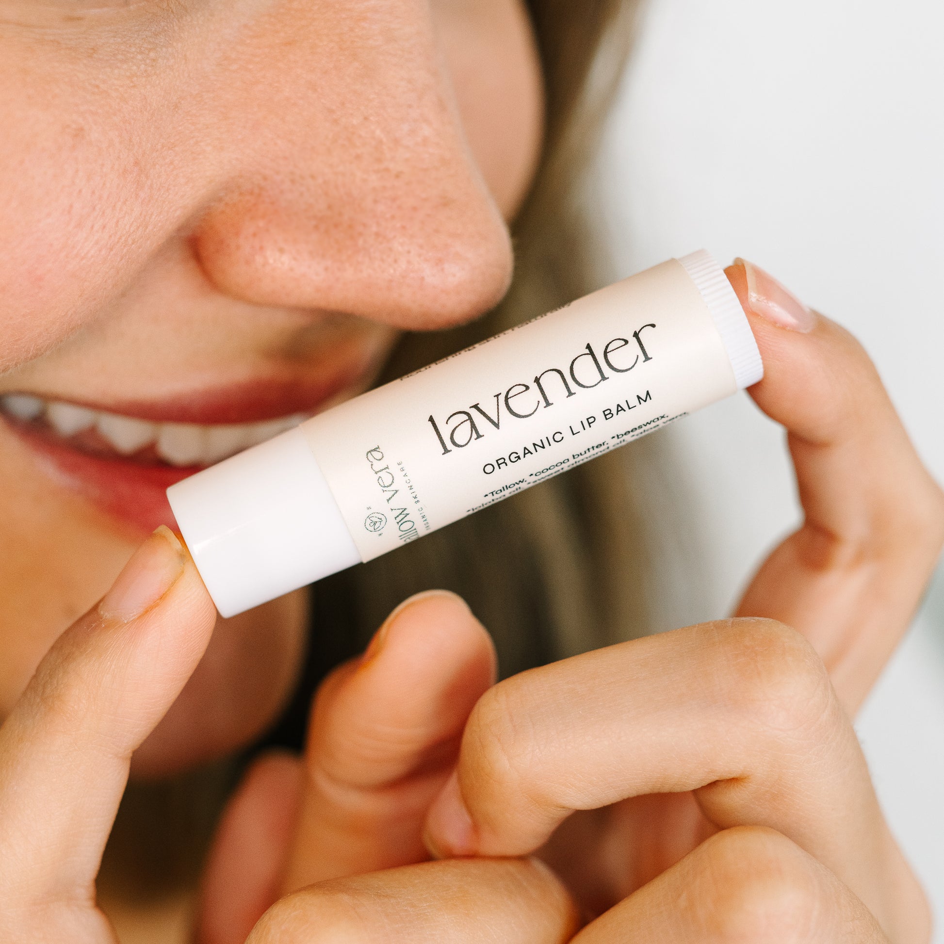 Girl holding Tallow Vera's organic lavender tallow lip balm with two fingers