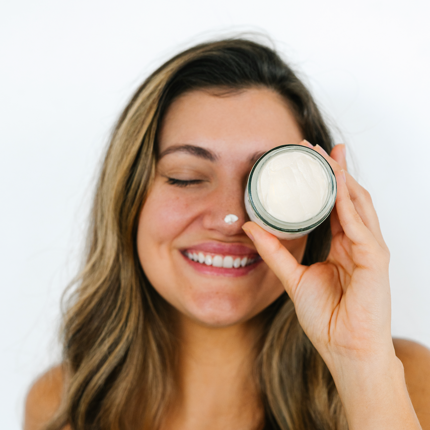 Woman applying tallow cream to her face with a white background.