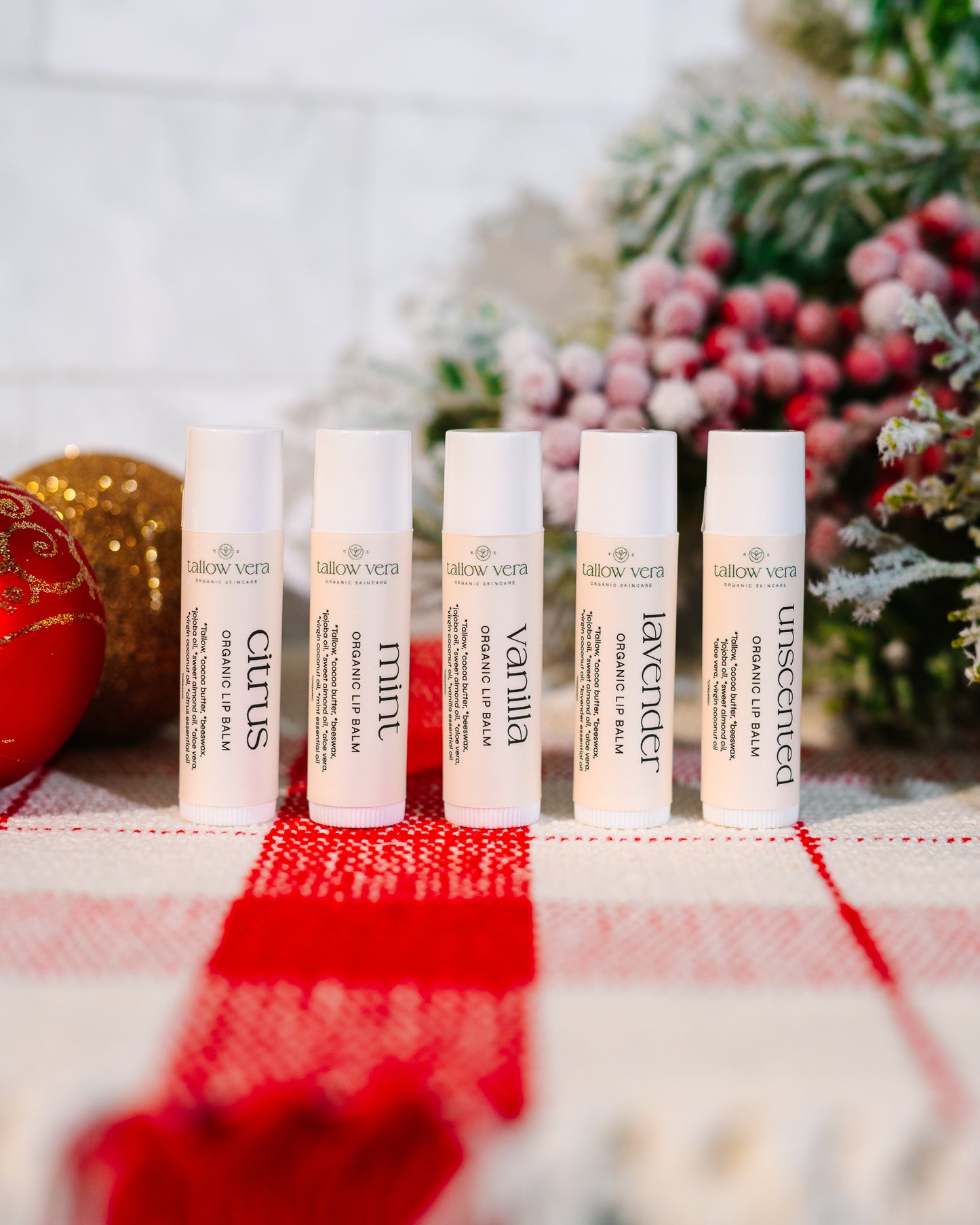 All 5 scent of Tallow Vera's organic tallow lip balms in front of Christmas decor