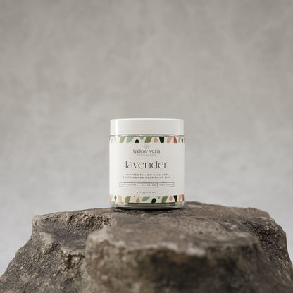 4oz Tallow Vera lavender whipped tallow moisturizer resting on a rock