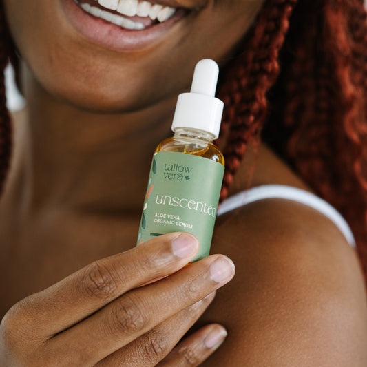 Girl holding a Tallow Vera aloe serum to her left shoulder and smiling